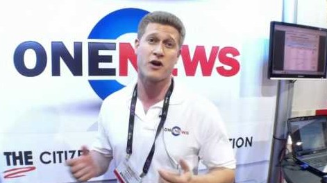 A man standing in front of a OneNews sign.