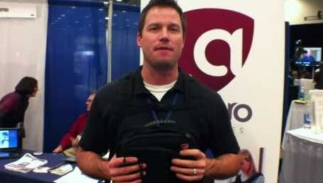 At MacWorld '11, a man is standing in front of a booth with a Defender Backpack.