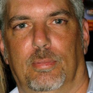 Close-up of a man with salt-and-pepper hair and a beard.