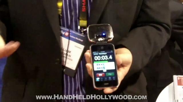 A man is holding up a cell phone with a microphone at CES.