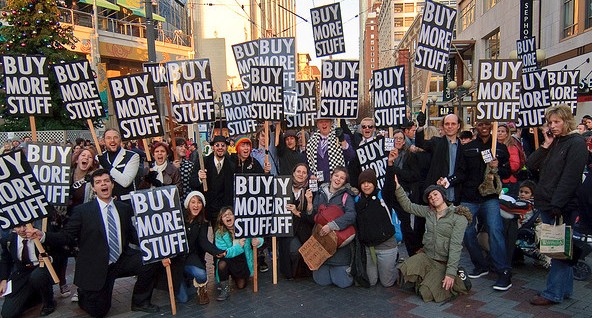 Group of Mobile Filmmakers holding signs with the phrase "buy more stuff" in a public demonstration.