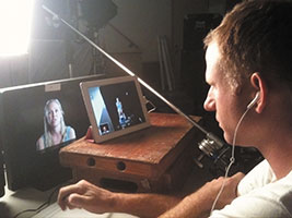 A man sitting at a desk with a laptop and earphones.