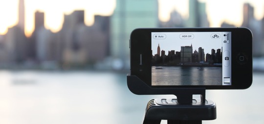 iPhone mounted on a tripod capturing a city skyline at dusk.
