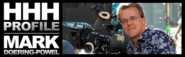 Man posing next to a camera on a film set, showcasing the pCAM Film+Digital Calculator.